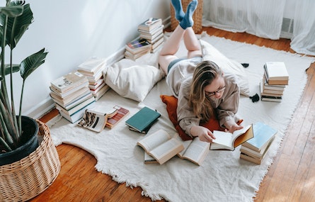 Photographie d'une femme allongée et entourée de piles de livres
